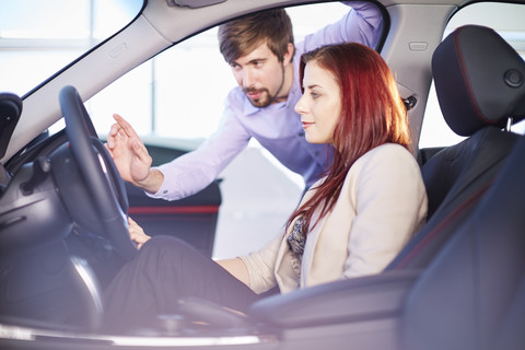 Car dealer talking to client inside car stock photo