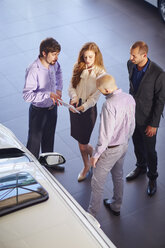 Car dealer meeting with clients in showroom - ZEF002044