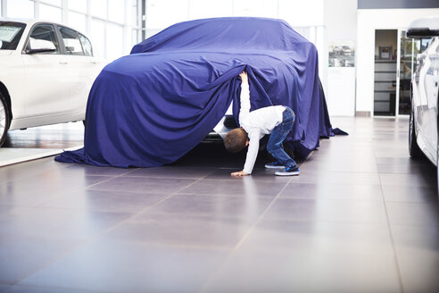 Boy at car dealer unveiling tarpaulin - ZEF002065