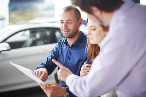 Ehepaar im Autohaus beim Kauf eines neuen Autos, lizenzfreies Stockfoto