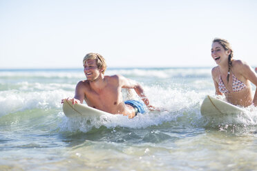 Glückliches junges Paar auf Surfbrettern im Meer liegend - ZEF002400