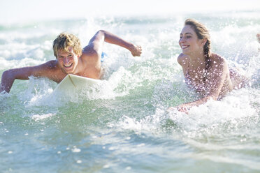Glückliches junges Paar auf Surfbrettern im Meer liegend - ZEF002405