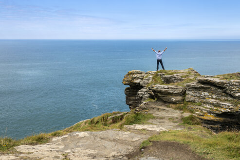 United Kingdom, England, Cornwall, Tintagel, North Coast, Tourist standing on rock - FRF000086