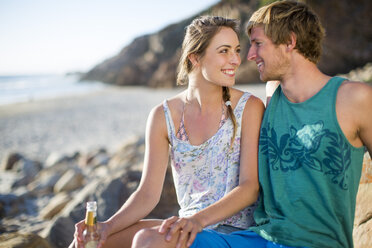 Glückliches junges Paar bei einem Drink am Strand - ZEF002413