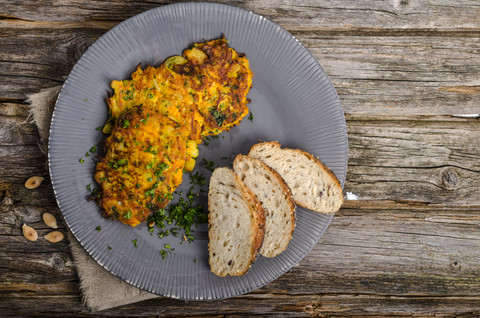 Teller mit Kürbis-Veggie-Burger und Vollkornbrotscheiben auf Holz, lizenzfreies Stockfoto