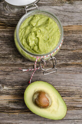 Preserving jar of avocado cream and half of avocado on wood - ODF000853