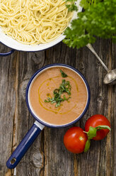 Pot of pasta, saucepan of tomato sauce, tomatoes and basil leaves on wood - ODF000855