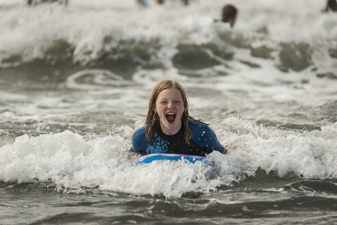 Portrait of screaming teenage girl with surfboard - PAF001042