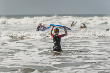 Junge trägt Surfbrett ins Meer - PAF001047