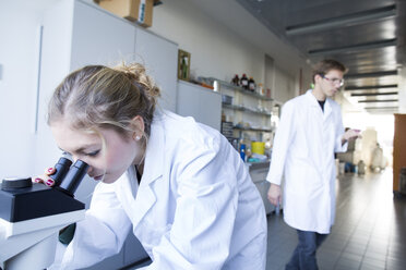 Young female chemist using microscope in a chemical laboratory - SGF000961