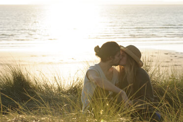 Young couple kissing at beach dunes in front of Atlantic - LAF001179