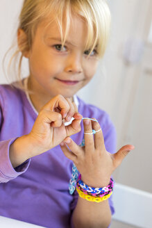 Porträt eines kleinen Mädchens, das Armbänder am Webstuhl herstellt - JFEF000527