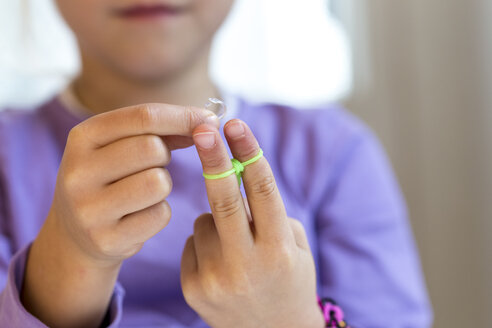 Finger eines kleinen Mädchens, das Armbänder am Webstuhl herstellt - JFEF000529