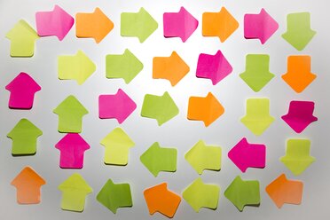 Coloured arrow shaped adhesive notes on white wall - SARF000989