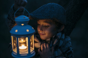 Italy, Grosseto, happy boy looking at lighted Christmas lantern by night - BEBF000011