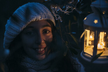 Italy, Grosseto, smiling girl with lighted Christmas lantern by night - BEBF000013