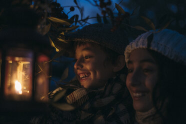 Italy, Grosseto, laughing siblings with lighted Christmas lantern by night - BEBF000015