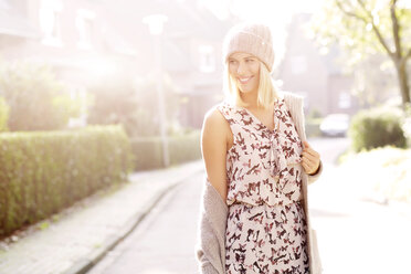 Porträt einer lächelnden blonden Frau in gemustertem Kleid, Strickjacke und Wollmütze - GDF000551