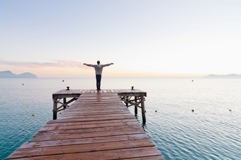 Spanien, Balearen, Mallorca, ein Jugendlicher steht morgens auf einem Steg, lizenzfreies Stockfoto