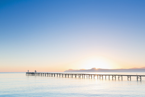 Spain, Balearic Islands, Majorca, people on a jetty at sunrise stock photo