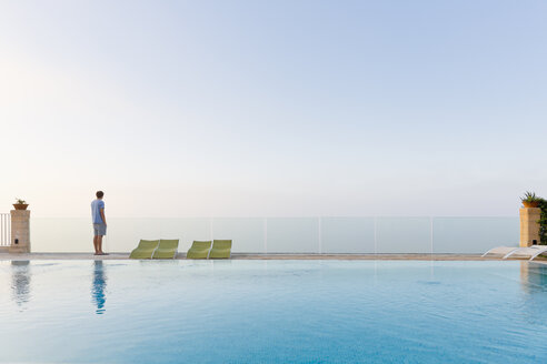 Spain, Balearic Islands, Majorca, one teenage boy standing on a safty glass rail at a swimmingpool - MSF004373