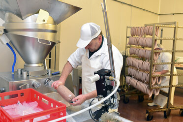 Mann bei der Wurstherstellung in einer Metzgerei - LYF000334