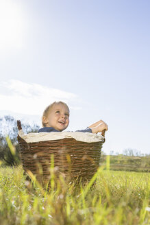 Kleiner Junge sitzt in einem Weidenkorb auf einer Wiese - OJF000068