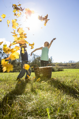 Zwei Kinder, die Herbstblätter in die Luft werfen, lizenzfreies Stockfoto