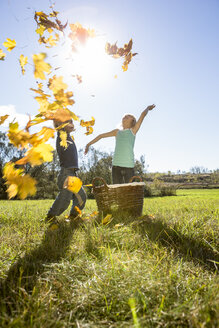Zwei Kinder, die Herbstblätter in die Luft werfen - OJF000071