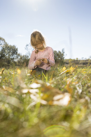 Serious looking girl sitting on a meadow stock photo