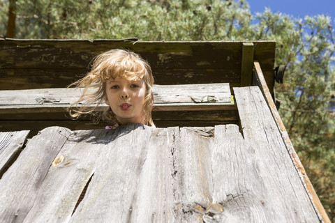 Mädchen im Baumhaus streckt Zunge heraus, lizenzfreies Stockfoto