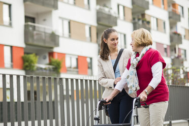 Granddaughter assisting her grandmother walking with wheeled walker - UUF002536