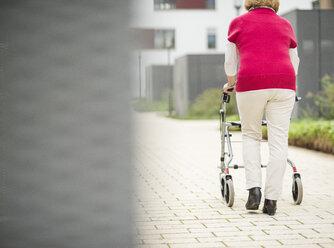 Ältere Frau geht mit Rollator, Rückenansicht - UUF002542
