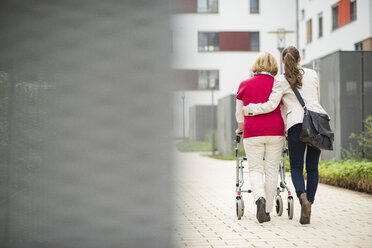 Granddaughter assisting her grandmother walking with wheeled walker - UUF002543