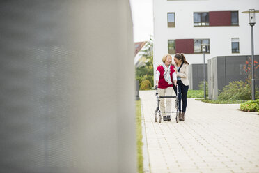 Granddaughter assisting her grandmother walking with wheeled walker - UUF002544