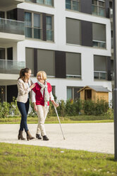 Granddaughter assisting her grandmother walking with crutch - UUF002558