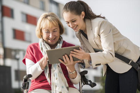 Enkelin und ihre Großmutter schauen auf ein digitales Tablet, lizenzfreies Stockfoto