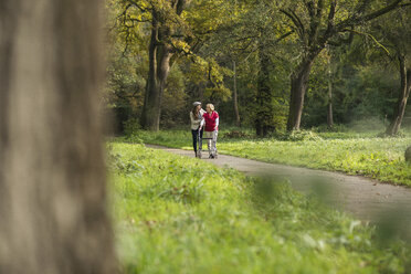 Ältere Frau und Enkelin gehen zusammen in einem Park spazieren - UUF002574