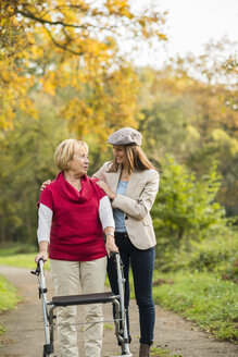 Ältere Frau und ihre erwachsene Enkelin gehen gemeinsam in einem herbstlichen Park spazieren - UUF002586