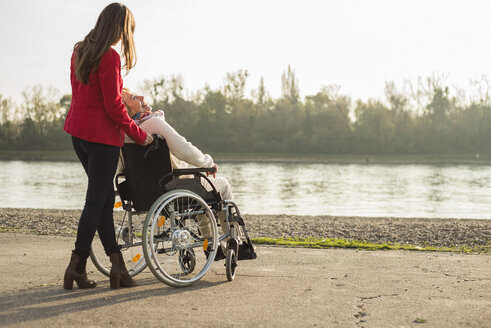 Erwachsene Enkelin, die ihrer im Rollstuhl sitzenden Großmutter hilft - UUF002626