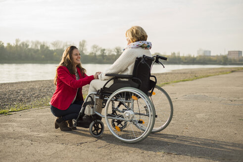 Erwachsene Enkelin, die ihrer im Rollstuhl sitzenden Großmutter hilft - UUF002591