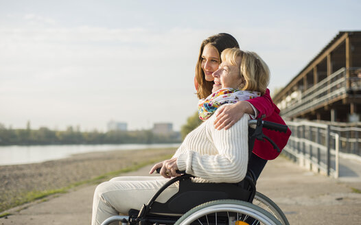 Enkelin, die ihre Großmutter im Rollstuhl sitzend umarmt - UUF002597