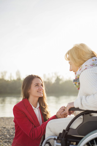 Enkelin Hand in Hand mit ihrer im Rollstuhl sitzenden Großmutter, lizenzfreies Stockfoto