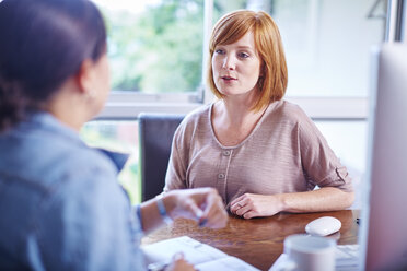 Two women sitting at home office table and working - ZEF002309