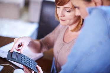 Two women in home office table using calculator - ZEF002312