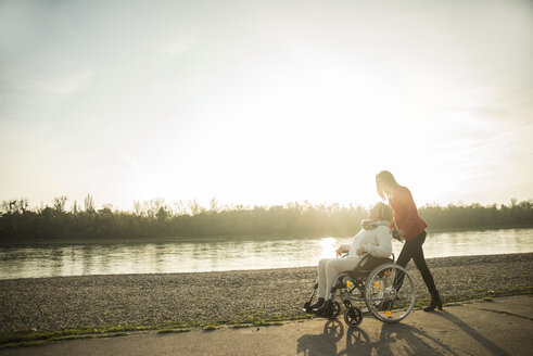 Erwachsene Enkelin, die ihrer im Rollstuhl sitzenden Großmutter hilft - UUF002612