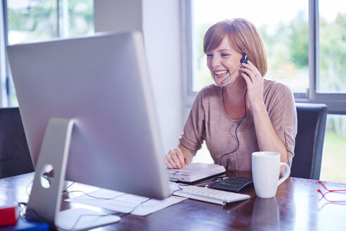 Woman at desk wearing a headset - ZEF002314