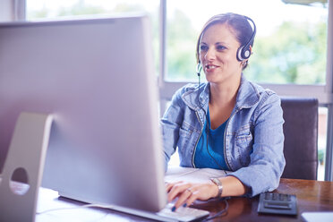 Woman at desk wearing a headset - ZEF002320