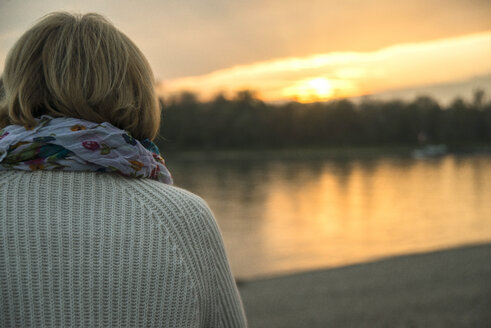 Ältere Frau beobachtet Sonnenuntergang, Rückenansicht - UUF002622