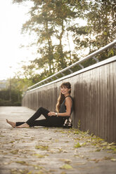 Lächelnde junge Frau entspannt sich auf einer Fußgängerbrücke - PAF001084